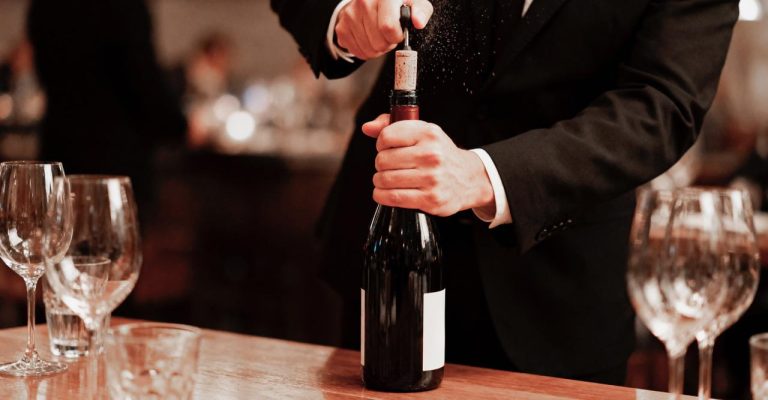 sommelier-uncorking-wine-bottle-restaurant-setting