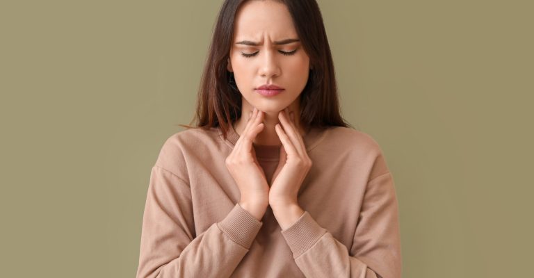 Young woman suffering from sore throat on color background